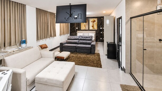 Una sala de estar moderna con un sofá, un reposapiés y un televisor de pantalla plana montado en la pared.