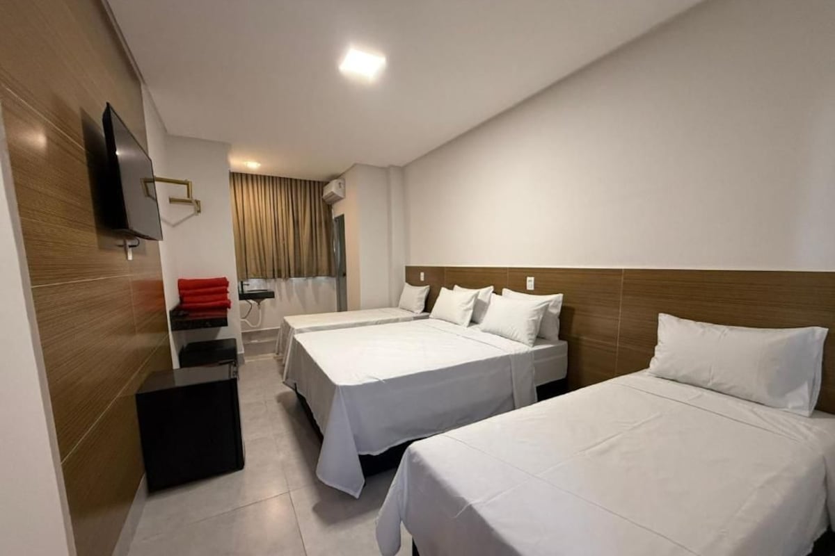 A hotel room with two beds, a flat-screen TV mounted on the wall, and a desk with a chair.