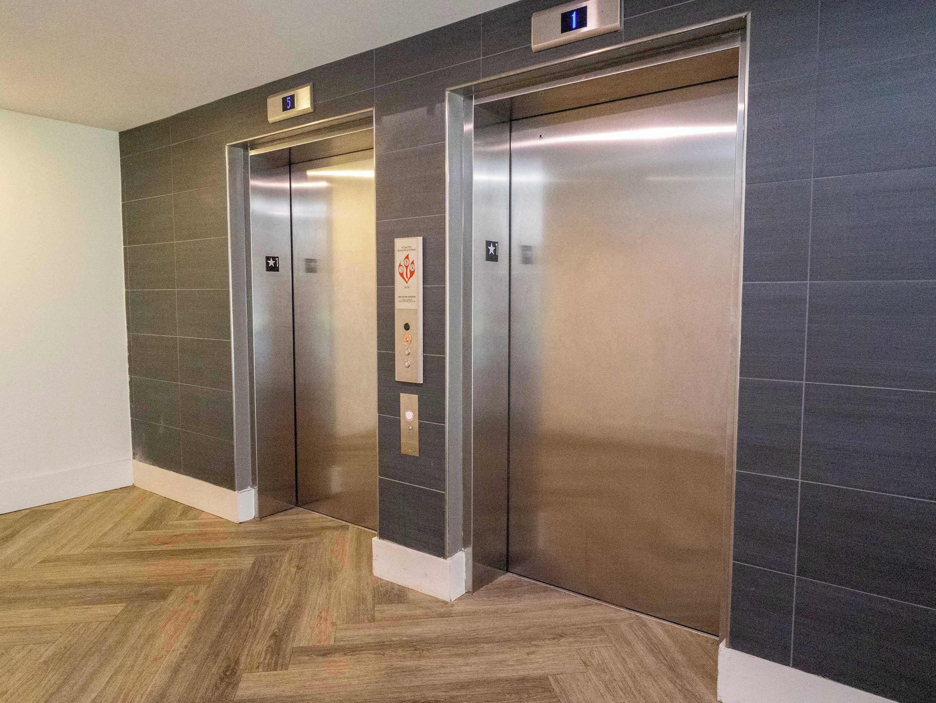 Twee liftdeuren met een digitaal display erboven en een bordje dat de richting van de lift aangeeft.