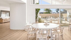 Een modern interieur met een ronde eettafel, omringd door stoelen, een grote witte kolom en uitzicht op een terras.