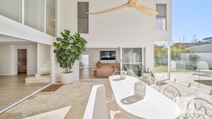 A modern house with a dining area, a large plant, and a ceiling fan. - Casa En Norah | Coastal Escape (Norah Head)