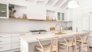 Een moderne keuken met witte kasten, een centraal eiland met barkrukken en hanglampen.