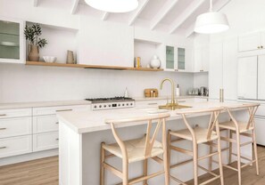 A modern kitchen with white cabinetry, a central island with bar stools, and pendant lighting.