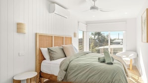 Quarto com cama, ventilador de teto e vista para o exterior.