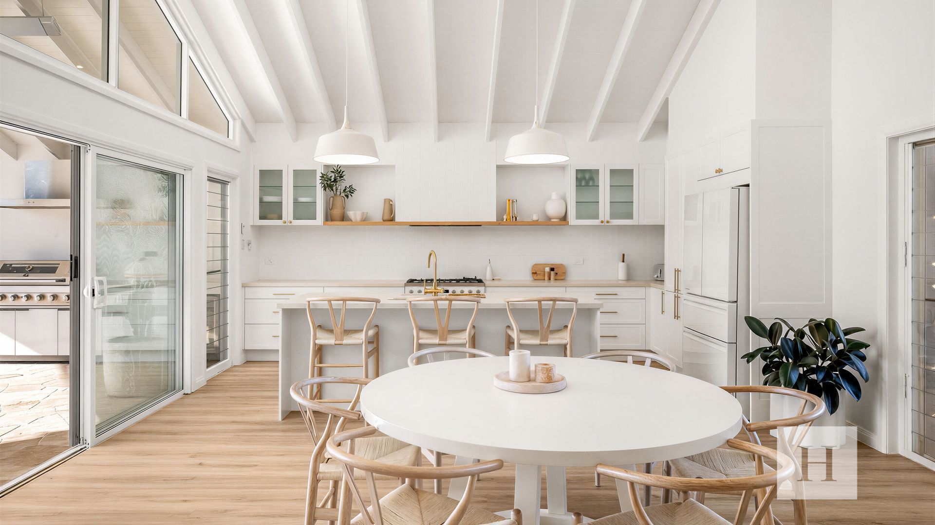 Une cuisine moderne avec des meubles blancs, un îlot central et un coin repas comprenant une table ronde et des chaises.