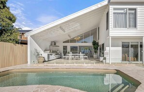 A modern house with a swimming pool, outdoor dining area, and a covered patio.