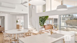 A modern kitchen with a marble countertop, a built-in sink, and a ceiling fan. - Casa En Norah | Coastal Escape (Norah Head)