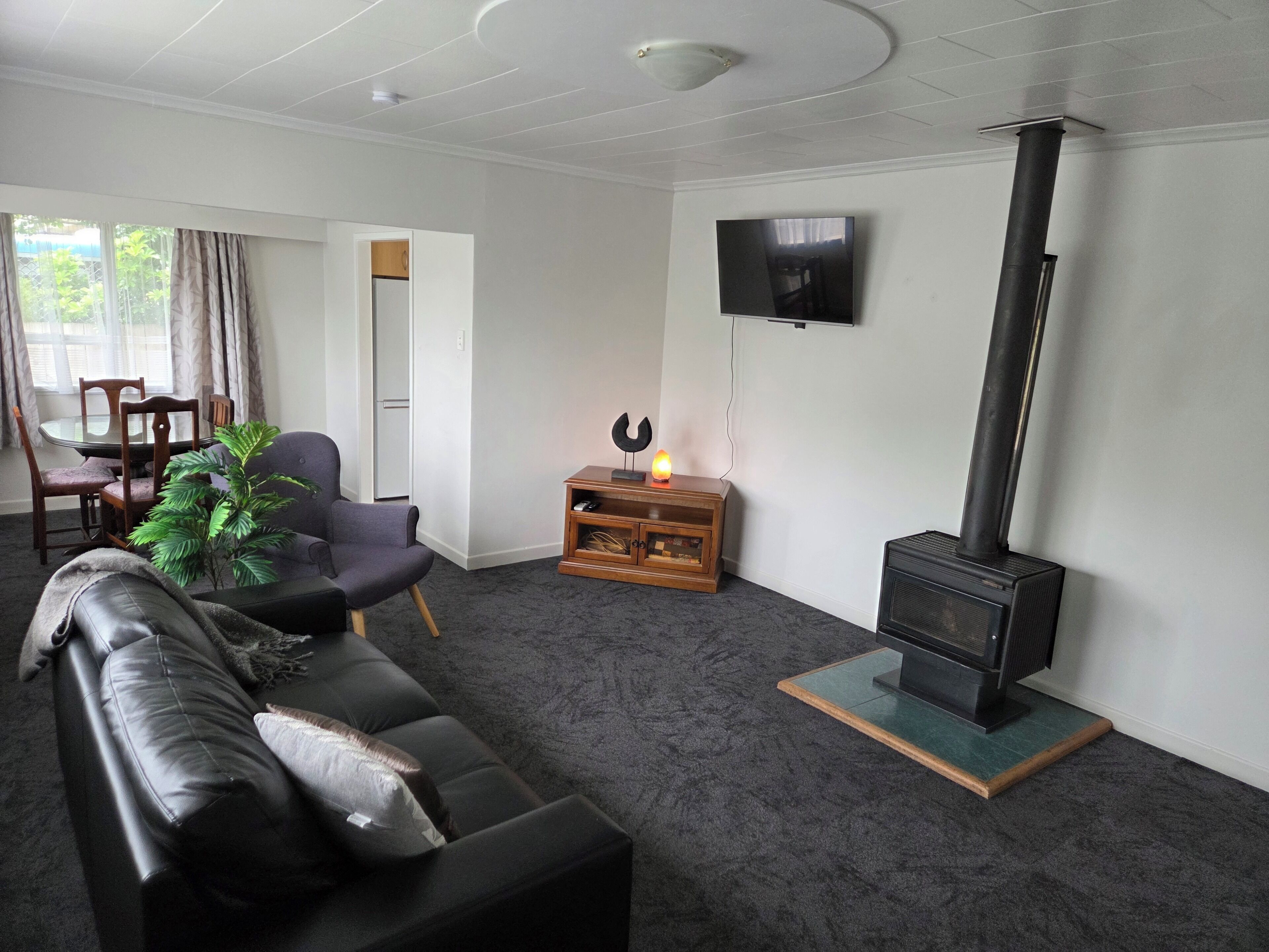 A living room with a sofa, a television, a fireplace, and a dining area with chairs and a table.