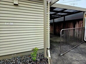 A building with a number '1/38' on the side, a metal gate, and a small plant in front.