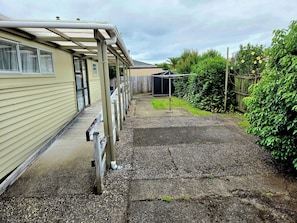 A covered outdoor area with a gravel path leading to a building with a wooden deck.