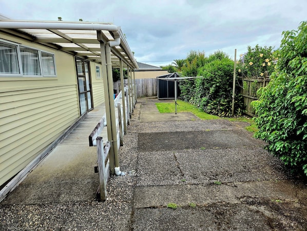 A covered outdoor area with a gravel path leading to a building with a wooden deck.