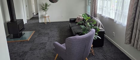 A living room with a sofa, a chair, a potted plant, a painting, and a fireplace.