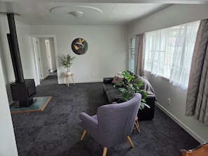 A living room with a sofa, a chair, a potted plant, a painting, and a fireplace.