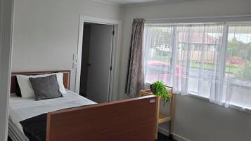 Una habitación de hotel con cama, mesita de noche, ventana con cortinas y vistas al exterior.