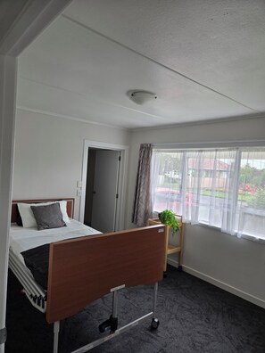 Une chambre d’hôtel avec un lit, une table de chevet, une fenêtre avec des rideaux et une vue sur l’extérieur.