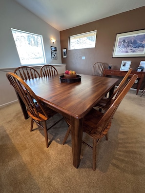 A dining room with a wooden table and chairs, a fruit bowl, and framed pictures on the walls. - Black Dog Inn - Minutes from The Gorge (Quincy)