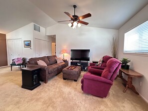 A living room with a brown sofa, a red armchair, a TV, and a ceiling fan. - Black Dog Inn - Minutes from The Gorge (Quincy)