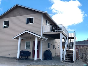 A two-story building with a covered porch, a red door, and a staircase leading to an upper level. - Black Dog Inn - Minutes from The Gorge (Quincy)