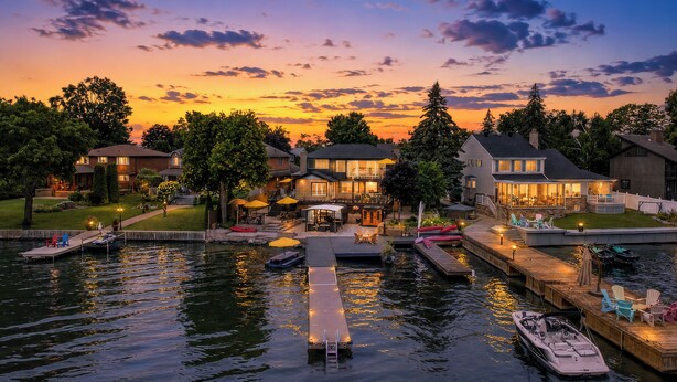 Une propriété située au bord de l’eau, dotée d’un quai, de bateaux et d’une terrasse bien éclairée.
