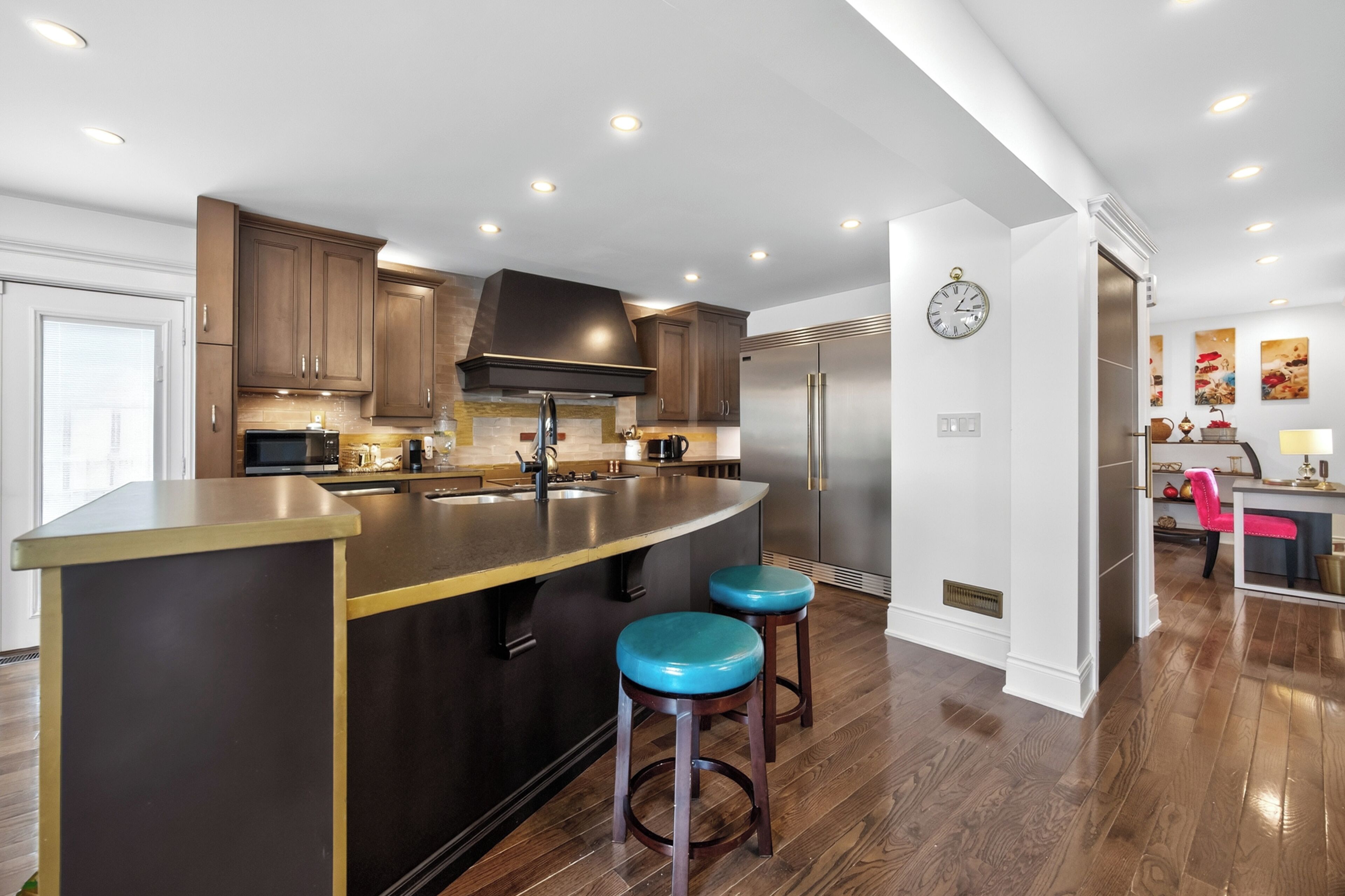 Una cocina moderna con una isla central, electrodomésticos de acero inoxidable y armarios de madera.