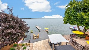 Une terrasse au bord du lac avec des sièges extérieurs, une jetée s’avançant dans l’eau et une vue sur le lac et la rive éloignée.