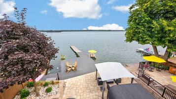 Une terrasse au bord du lac avec des sièges extérieurs, une jetée s’avançant dans l’eau et une vue sur le lac et la rive éloignée.
