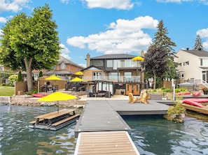 A waterfront property with a dock, outdoor seating, and a building with a balcony.
