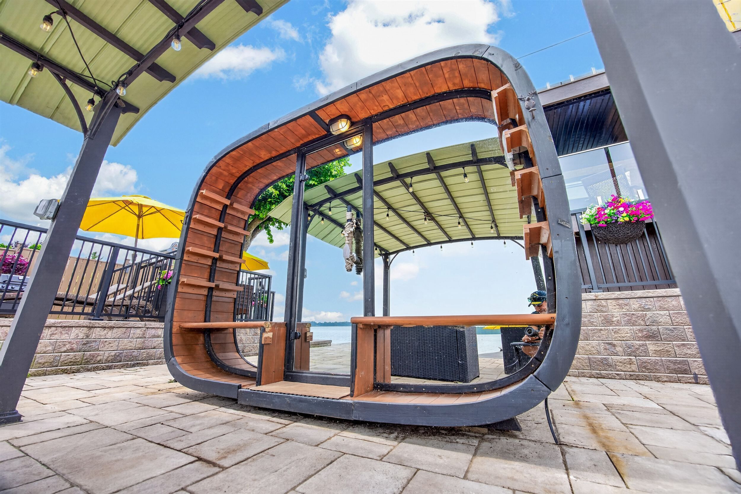 Una estructura de madera curva con un banco, un espacio cubierto con techo y vistas al agua.