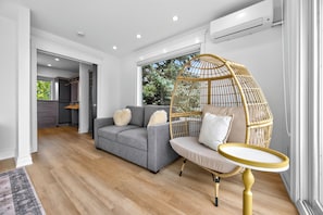 A modern living room with a grey sofa, a rattan chair, and a small round table.