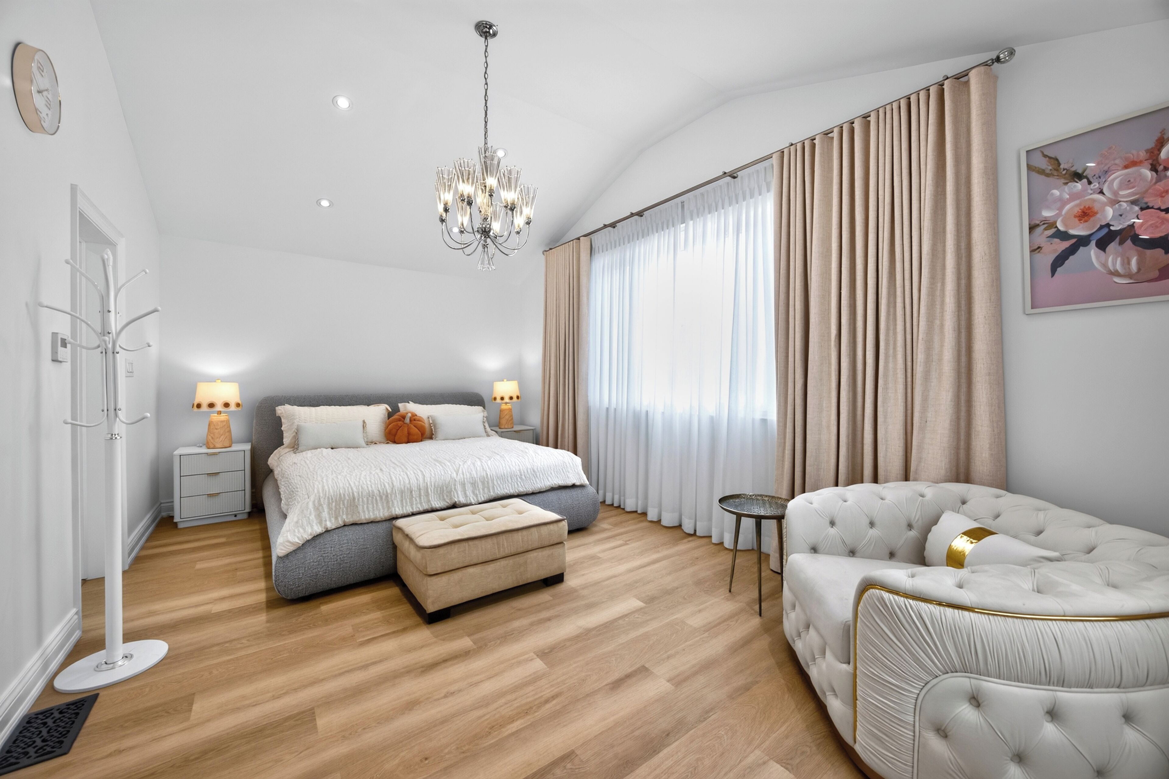 Quarto moderno com cama grande, área de estar e lustre.
