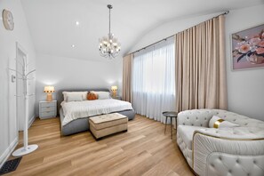 A modern bedroom with a large bed, a sitting area, and a chandelier.