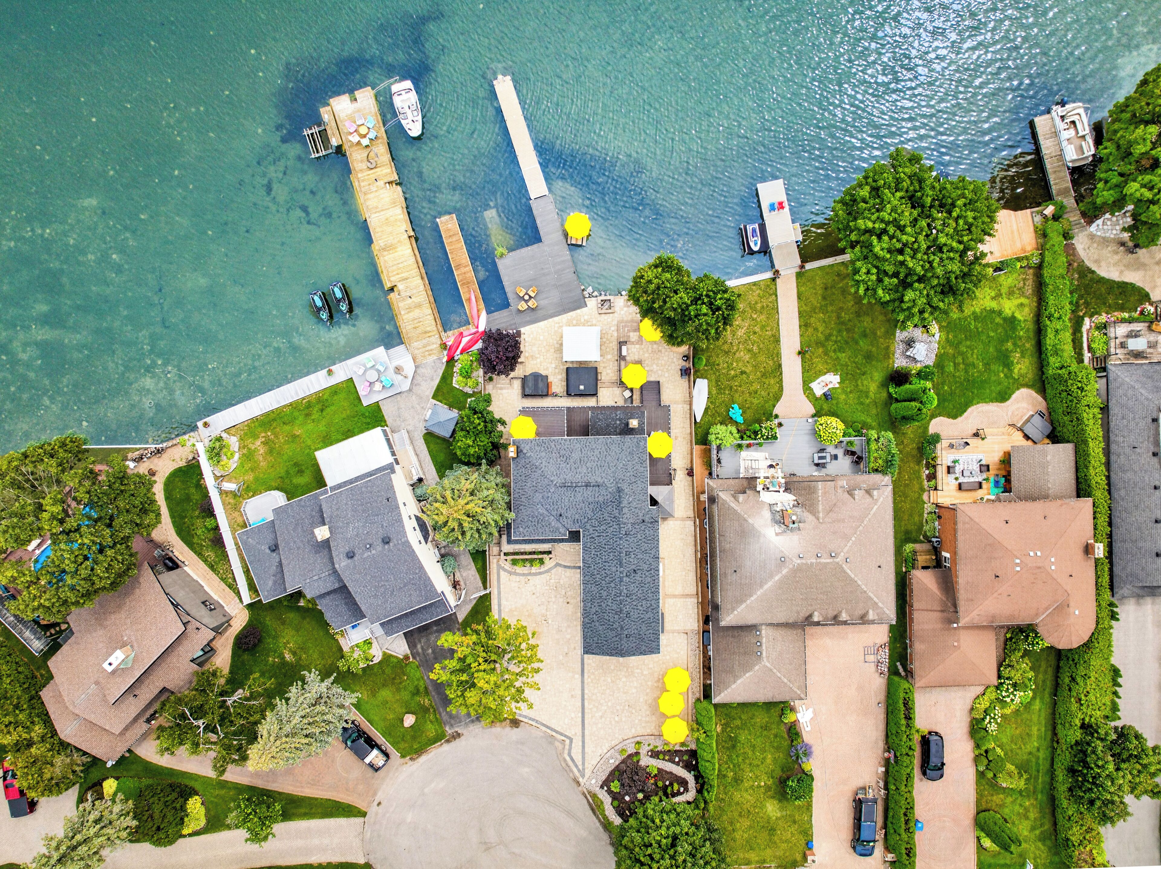 An aerial view of a residential area with a dock, boats, and a well-maintained lawn.