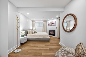 A modern bedroom with a bed, bedside table, lamp, and a fireplace.
