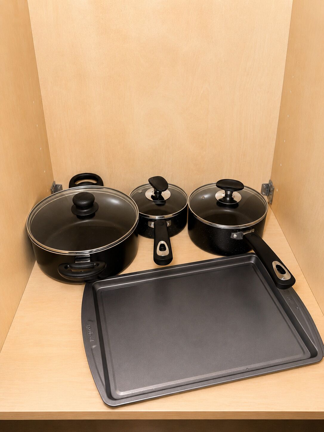 Een keuken met een zwarte koekenpan, twee pannen en een bakplaat.