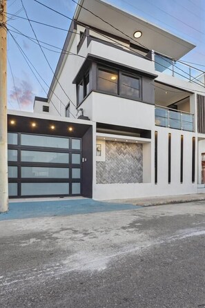 A modern two-story house with a garage, large windows, and a herringbone-patterned wall. - Arecibo 3BR | Beach Views | Jacuzzi (Arecibo)