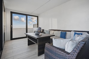 A balcony with a wicker table and sofa, a view of the sky, and a door leading outside. - Arecibo 3BR | Beach Views | Jacuzzi (Arecibo)