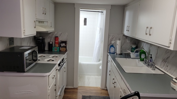 A compact kitchen with a microwave, stove, and sink.