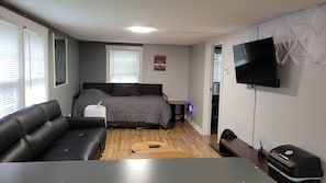 Ett litet sovrum med en säng, en soffa, ett litet bord, en tv och en värmare.