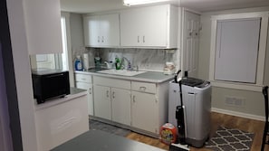 A compact kitchen with white cabinets, a microwave, a sink, and a small refrigerator.