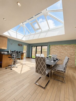 A modern kitchen with a skylight, a dining area with patterned chairs, and a view of the outside. - Large 6 bedroom house in Oxford near John Radcliffe Hospital with parking for (Oxford)