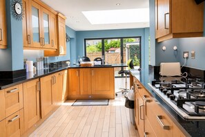 A modern kitchen with wooden cabinets, a black countertop, and a gas stove. - Large 6 bedroom house in Oxford near John Radcliffe Hospital with parking for (Oxford)