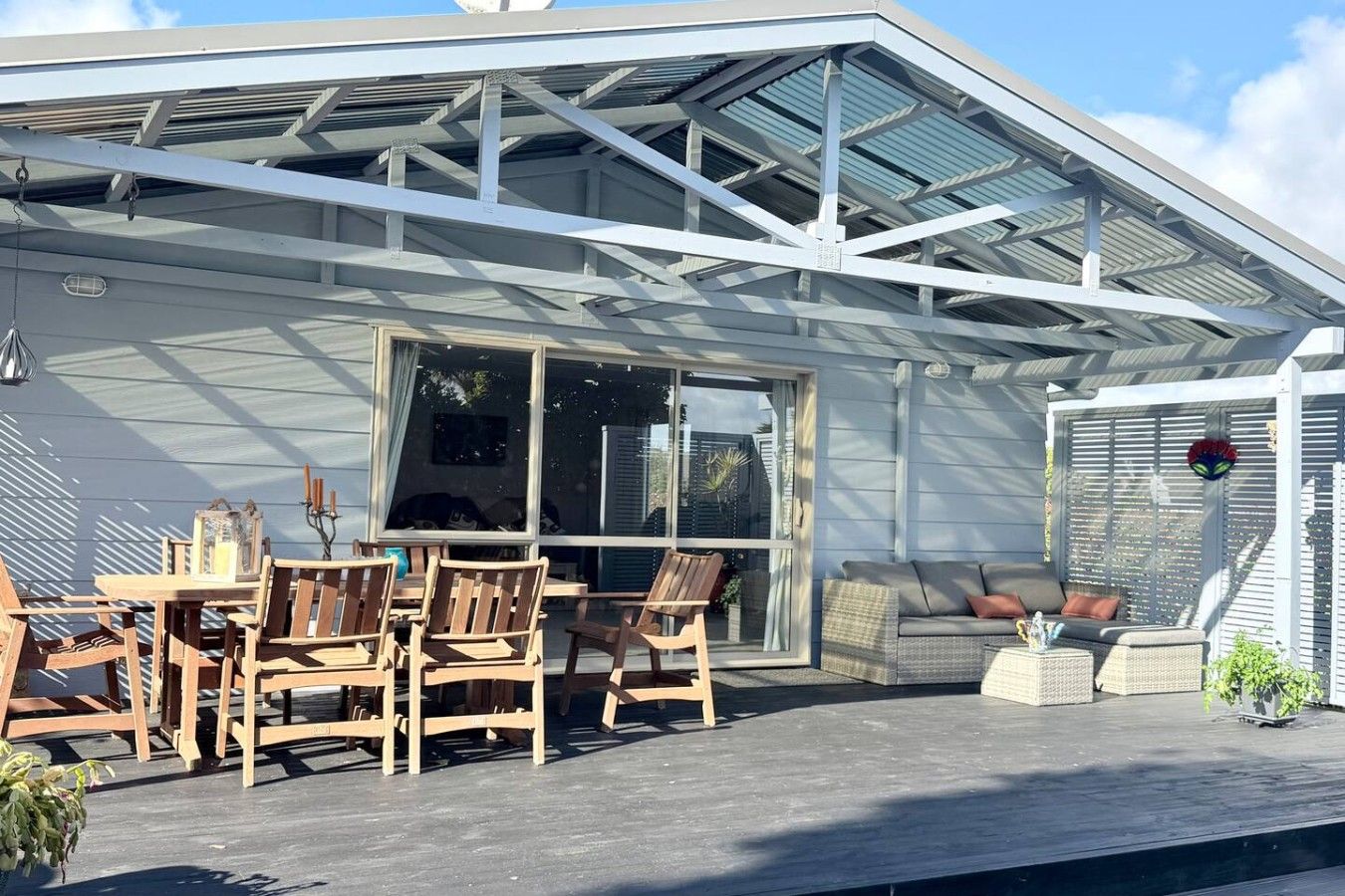A covered patio with a table and chairs, a sofa, and a potted plant.