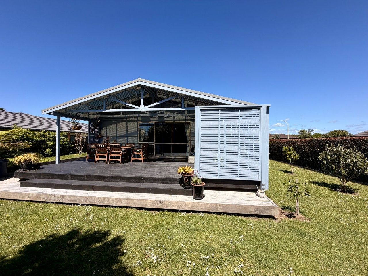 Une maison moderne dotée d’un patio couvert, d’un espace salon extérieur et d’une grande fenêtre.