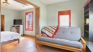 A room with a bed, a sofa, a television, and a window with blinds. - Charming Historic Las Cruces House & Farmers Market (Las Cruces)