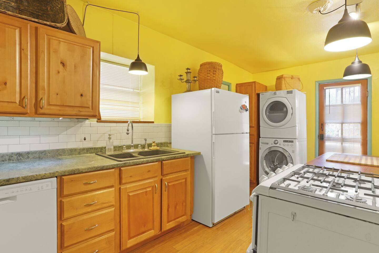 A kitchen with wooden cabinets, a white refrigerator, a built-in washing machine, and a gas stove.