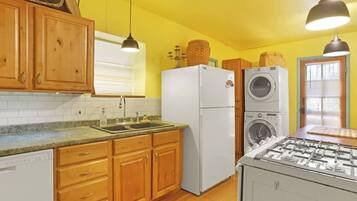 A kitchen with wooden cabinets, a white refrigerator, a built-in washing machine, and a gas stove.
