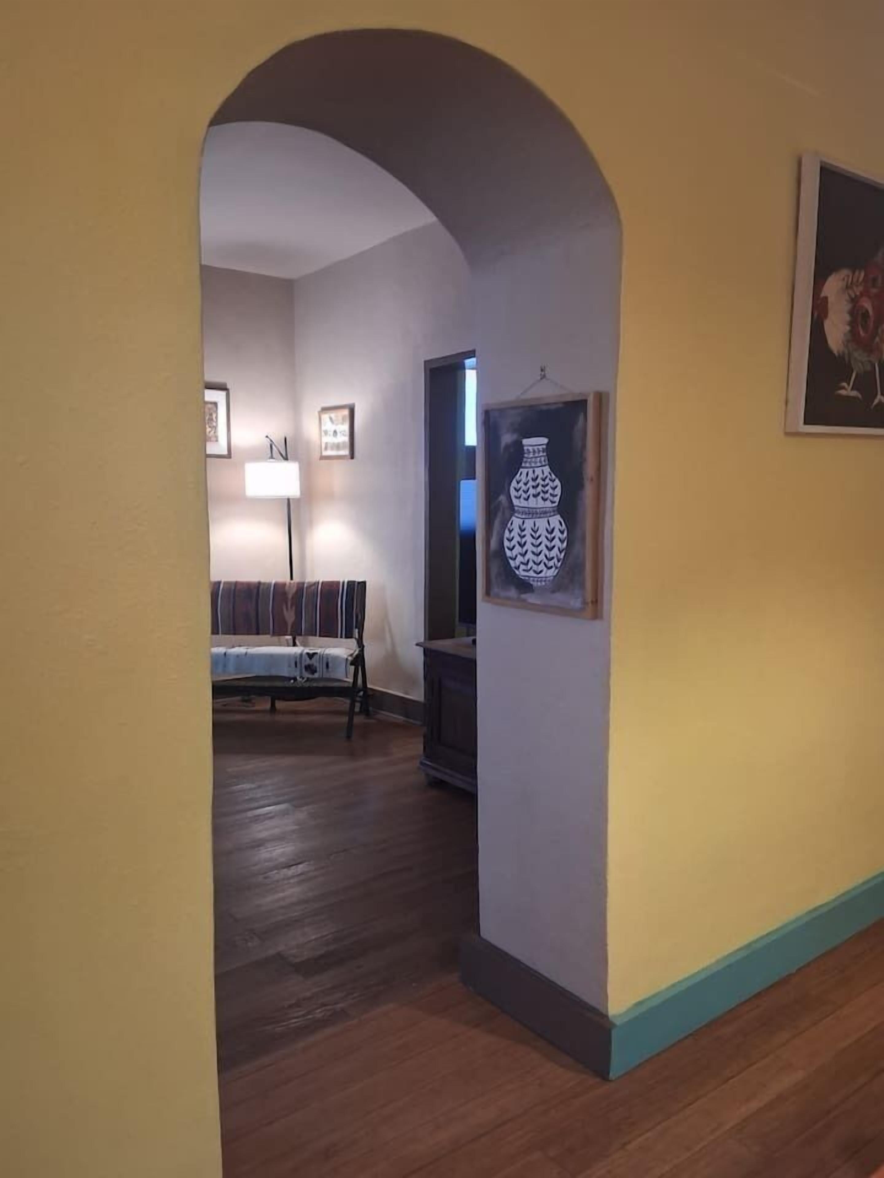 Un couloir avec un plancher en bois, un canapé, une lampe et un tableau encadré au mur.