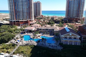 A resort with multiple swimming pools, a beach, and high-rise buildings in the background. - Portofino- Gulf Front with Beautiful Sunsets! (Escambia County)