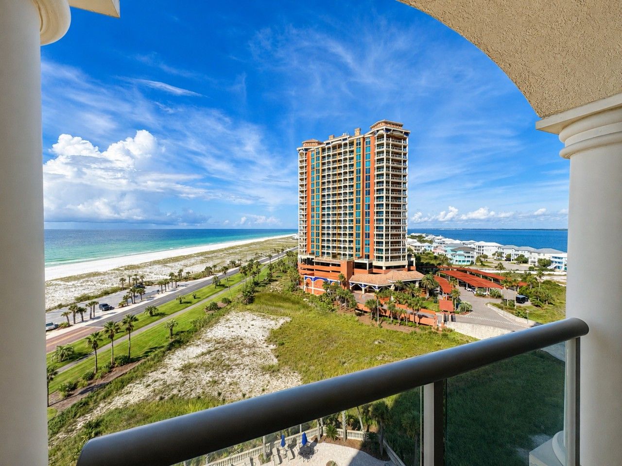 Hotel alto com vista para a praia, destacando um edifício com várias varandas e área ajardinada ao redor.