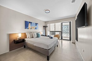 Een moderne hotelkamer met een groot bed, een flatscreen televisie, een schilderij en uitzicht op de stad.
